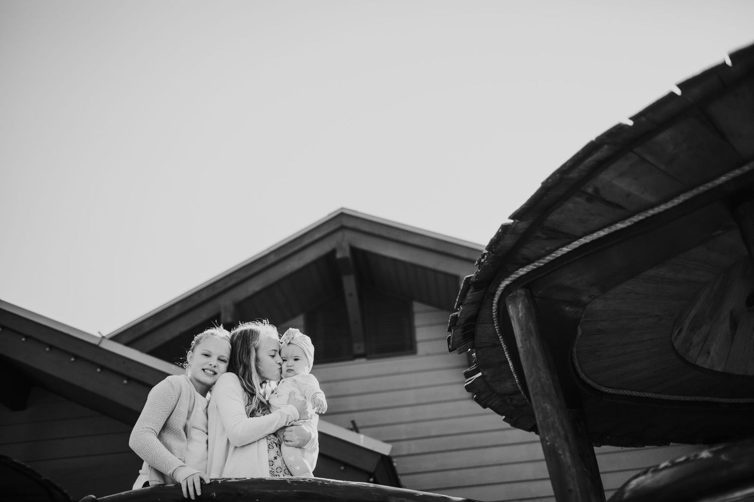 A black and white photo of kids embracing outdoors at a playground.