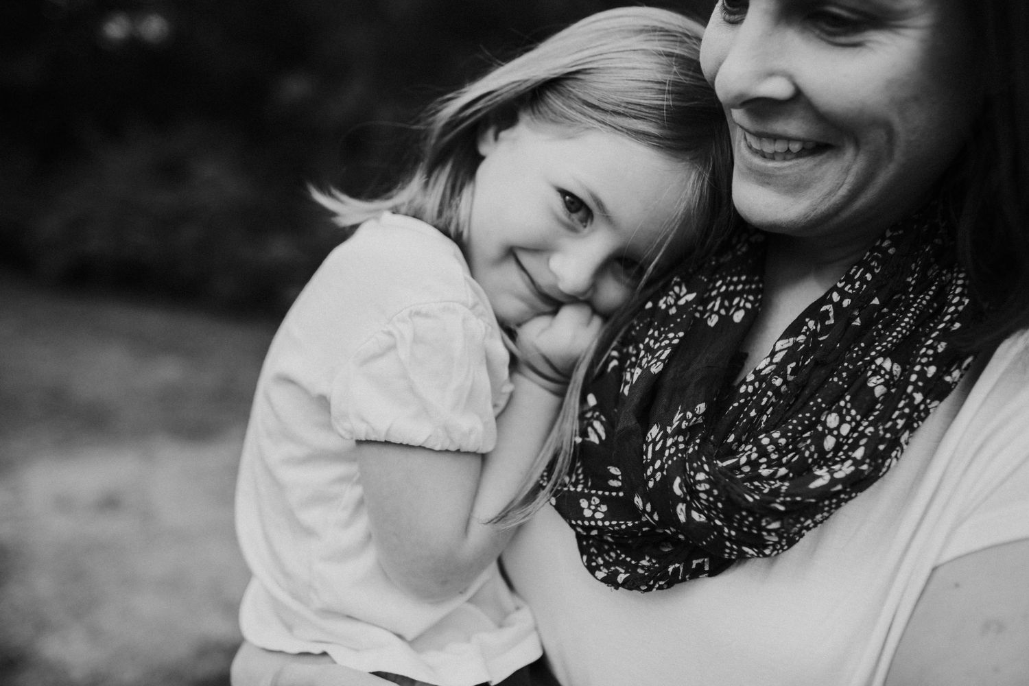 A young daughter cuddles up to her mom's shoulder.