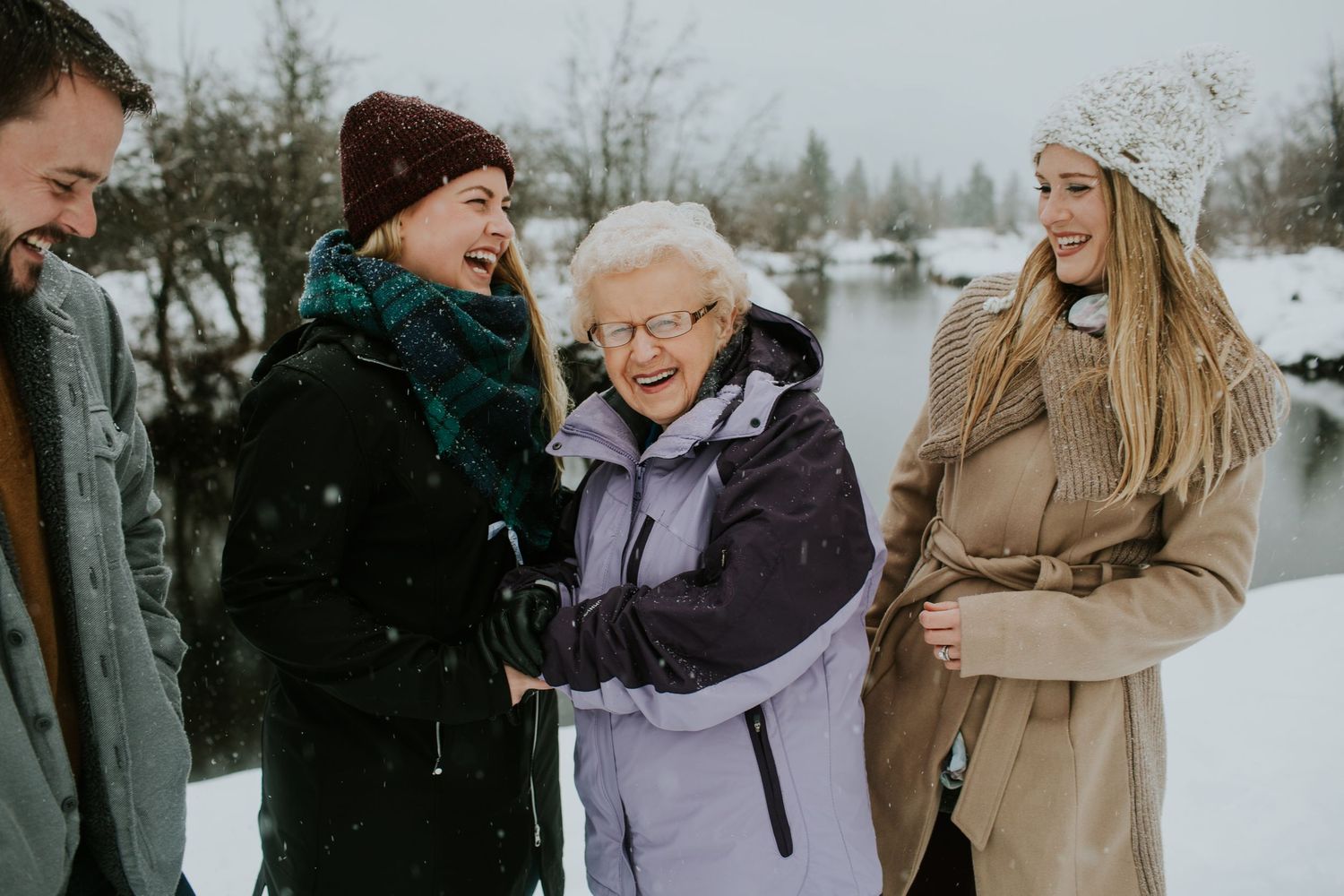 Grandma with adult grandkids laughing together in the snow.