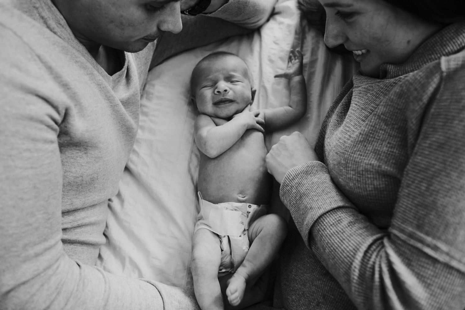 A couple laying on bed with newborn baby.