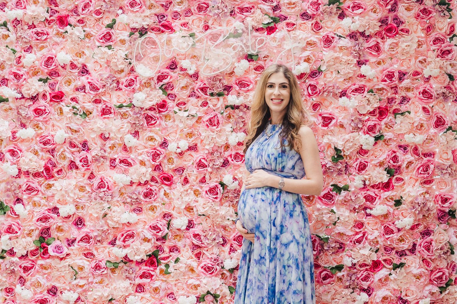 expecting mother in front of a flower wall at her baby shower in river oaks