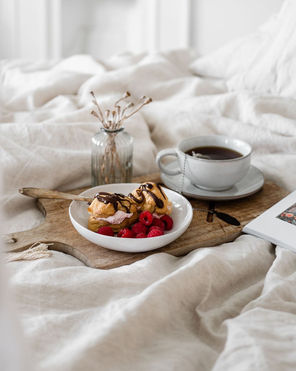 A rustic breakfast scene with coffee, pastries, and fresh berries arranged on white linens and wooden serving boards.