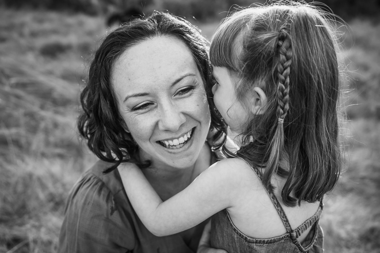 Black and white photo of mother daughter sharing a secret.