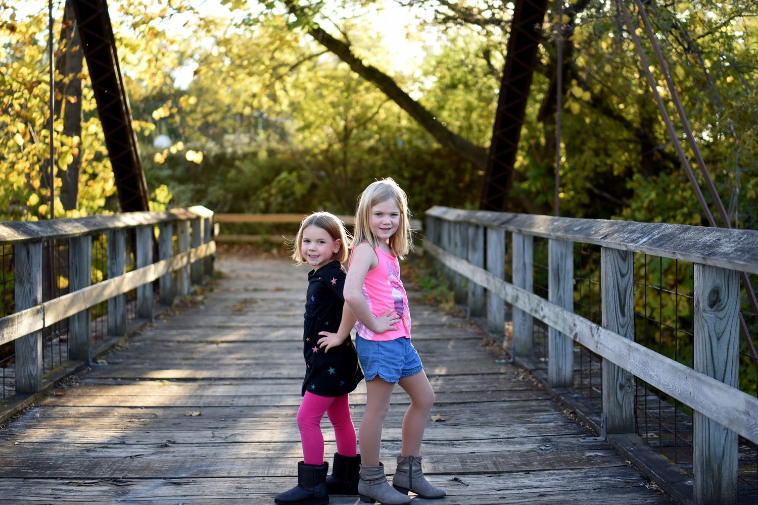 Outdoor portrait session on a wooden bridge with natural fall foliage in background.
