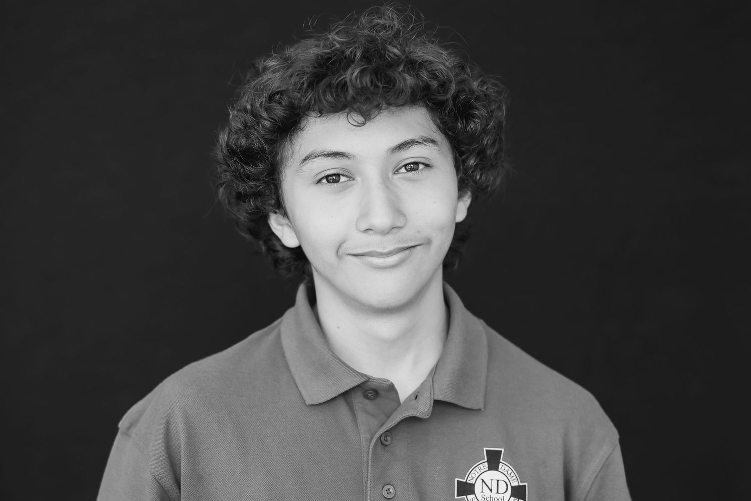 Black and white portrait of student in polo shirt with curly hair.