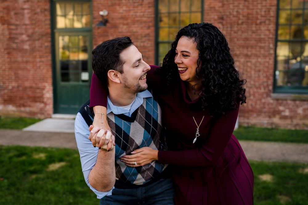 Joyful couples laughing together against a rustic brick building exterior.