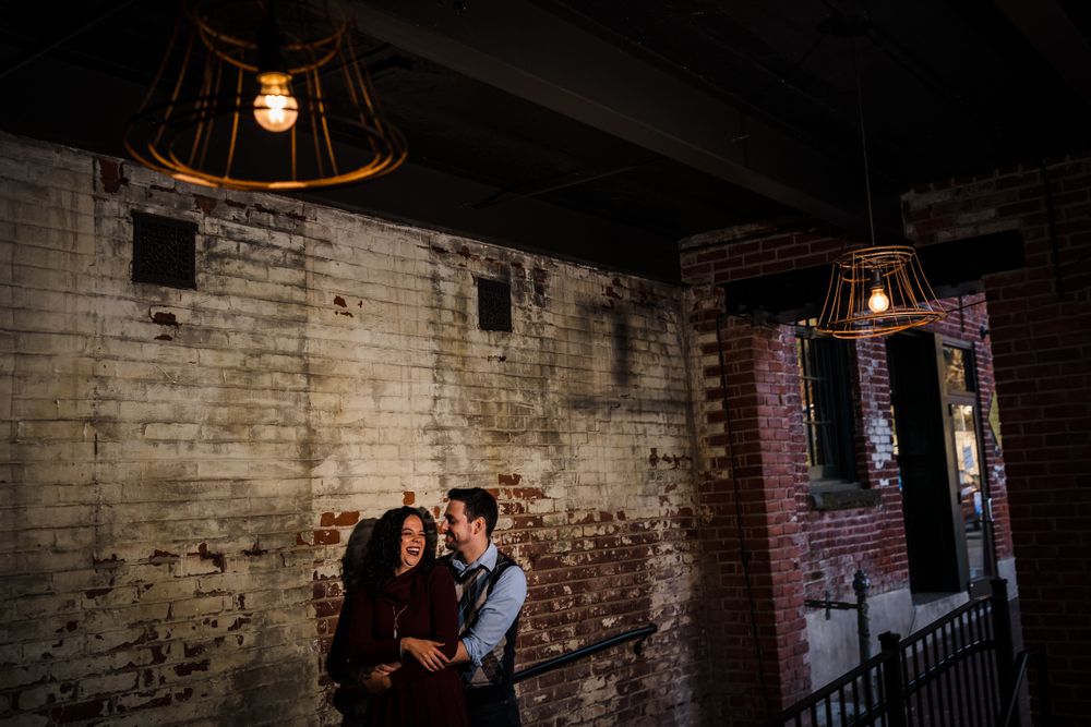 Couple in an industrial brick interior with moody lighting and exposed walls.