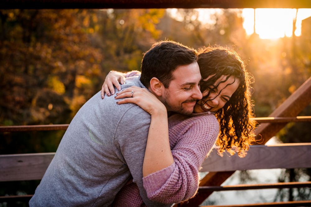 Couple sharing an intimate moment at sunset in a park setting with golden light filtering through trees.