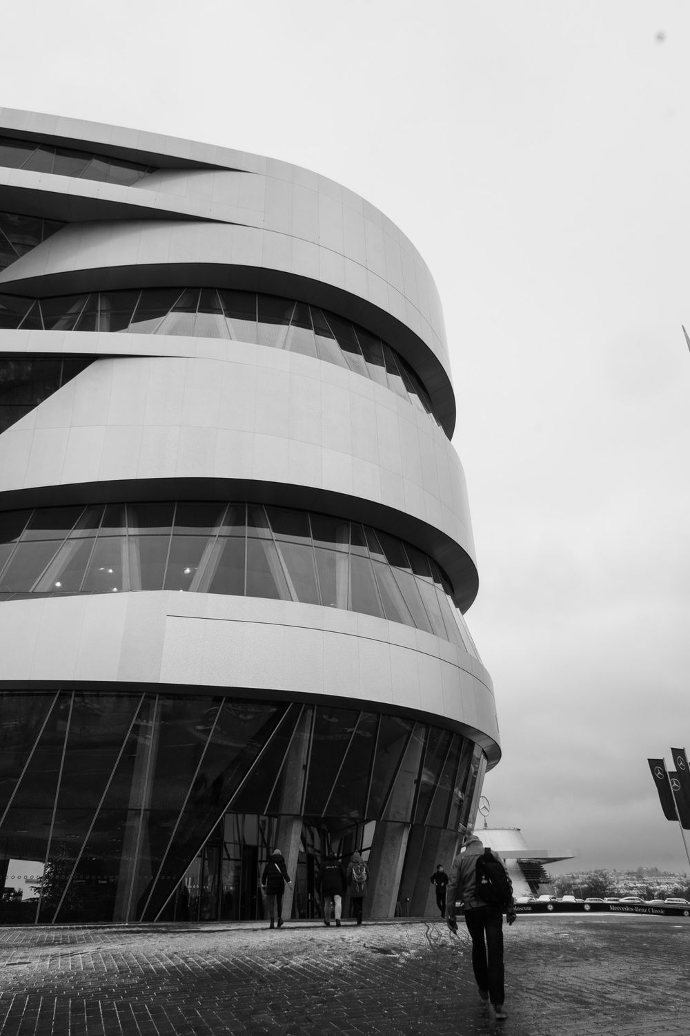 Black and white exterior view of the modern spiral Mercedes-Benz Museum building in Stuttgart.