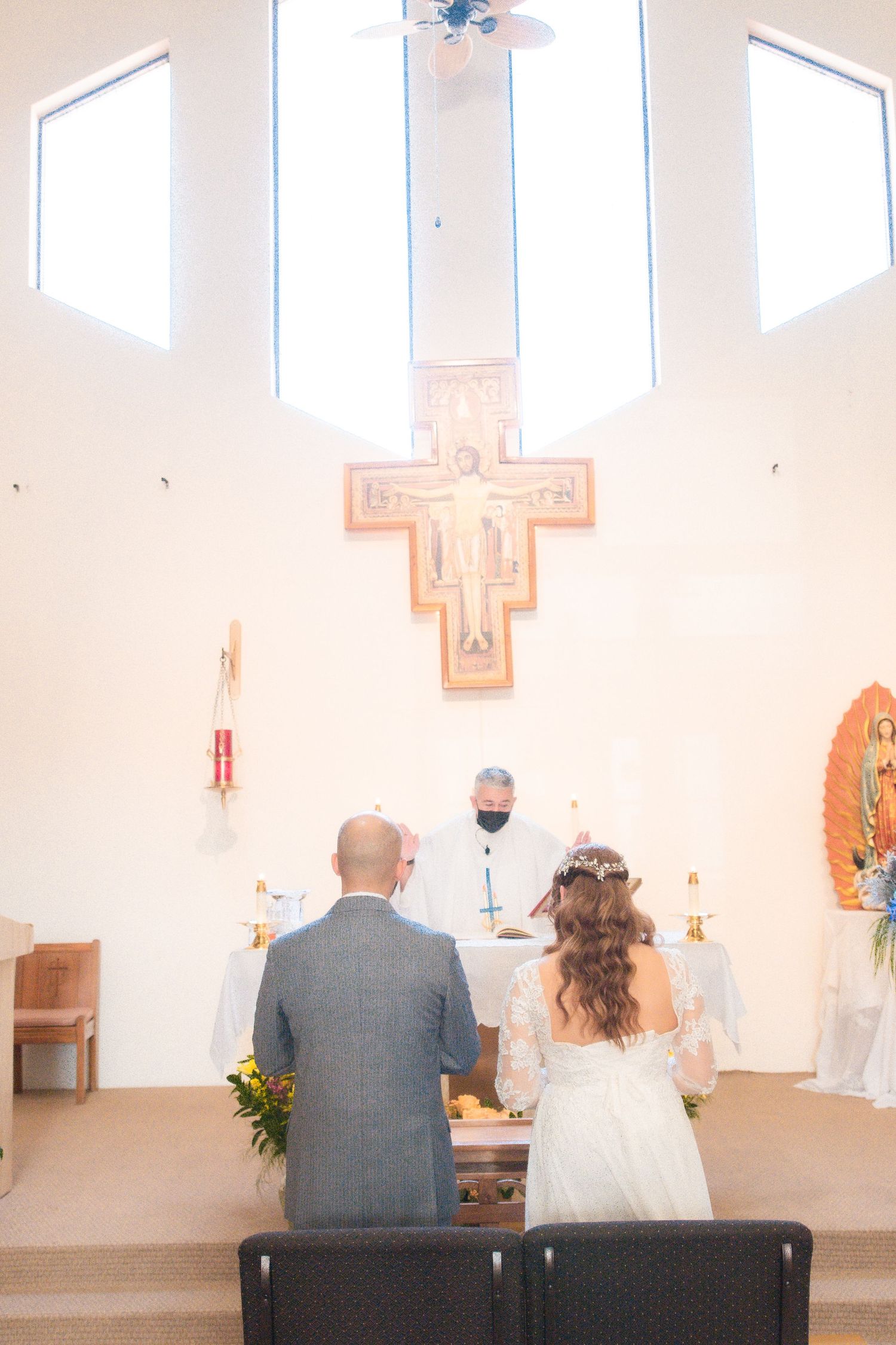 Wedding ceremony in a bright modern church with white walls and cross details.