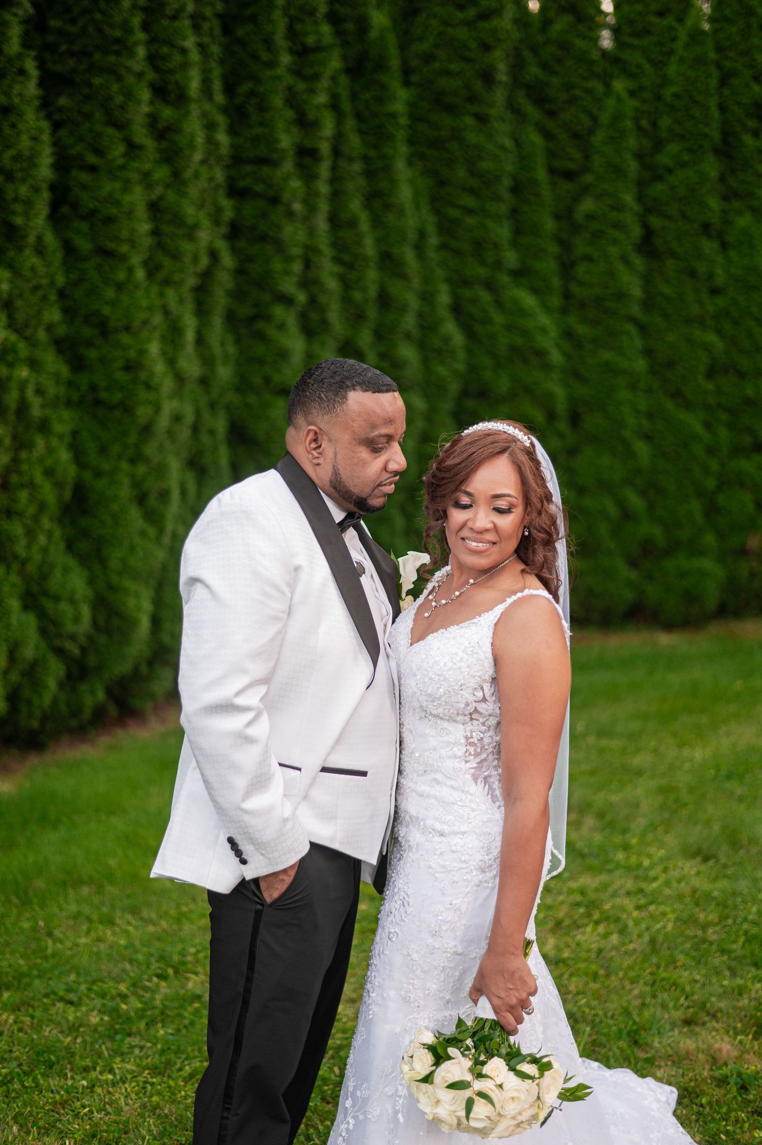Romantic wedding portraits against lush green hedges in outdoor garden setting.