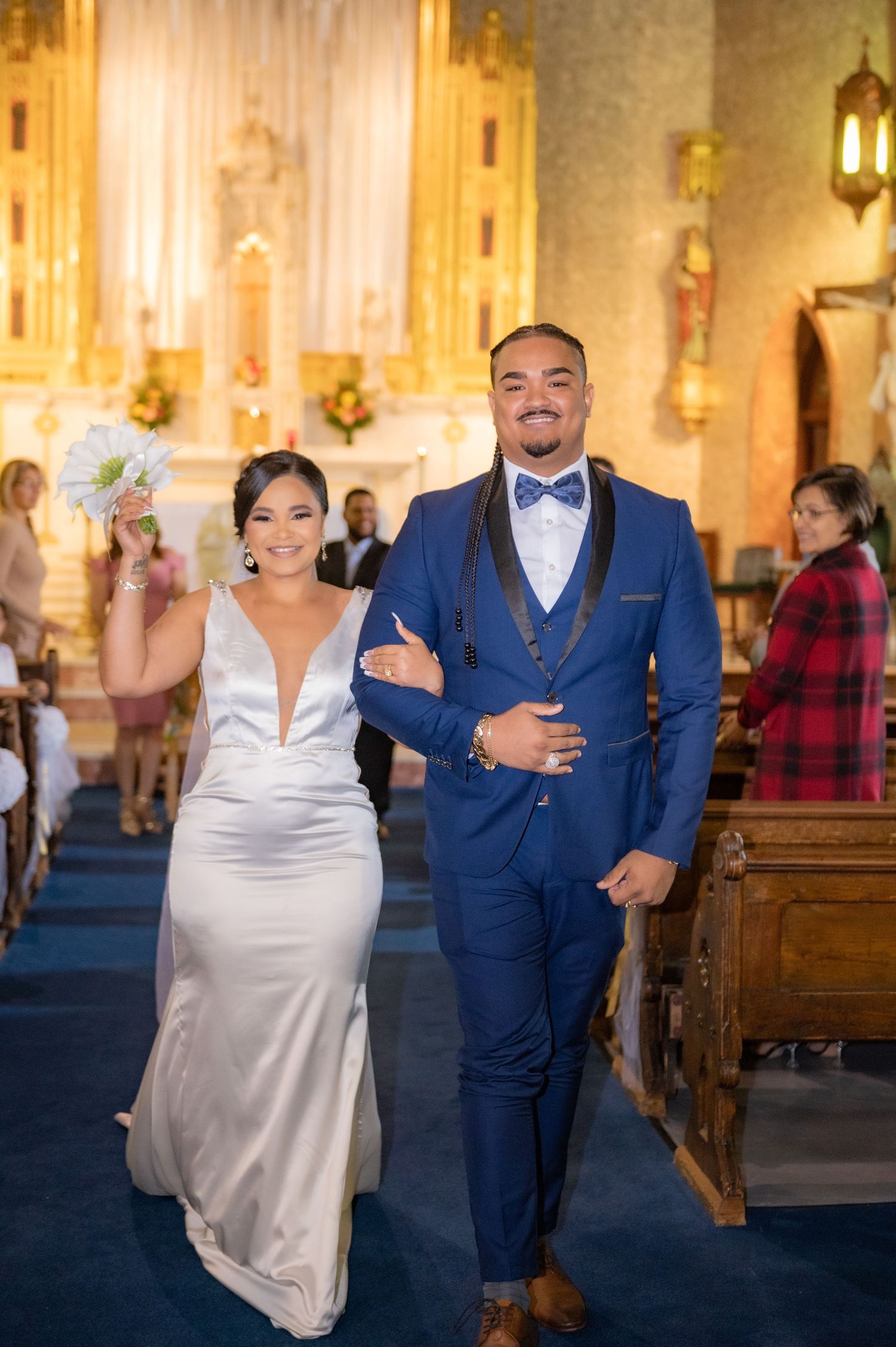 Joyful wedding exit down church aisle with navy and white attire.