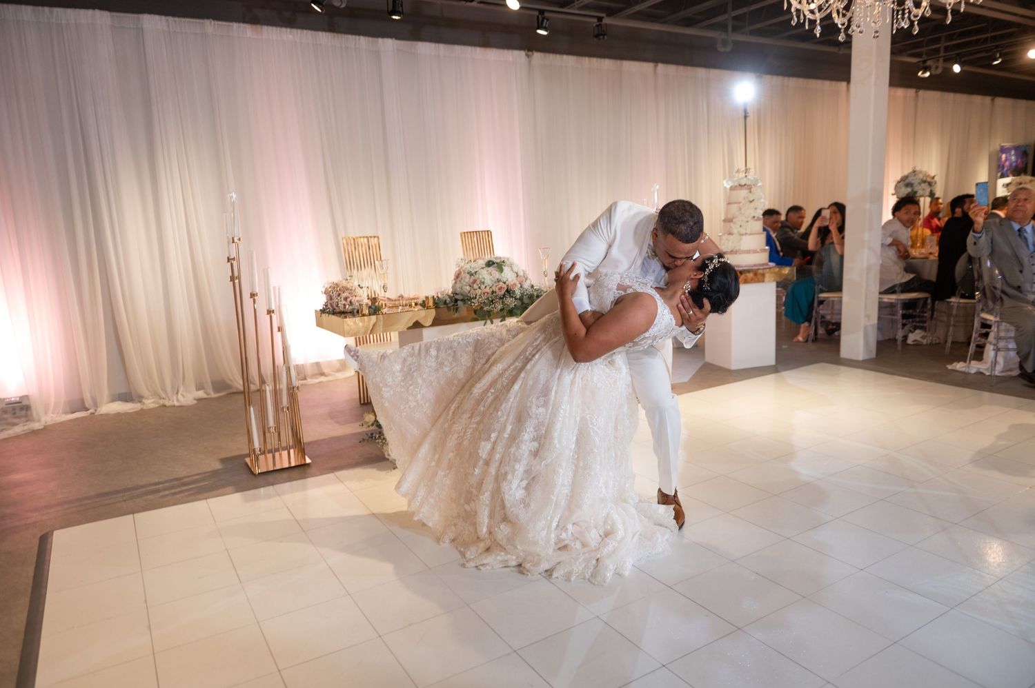 An elegant white wedding reception space with crystal chandeliers and draped fabric walls.