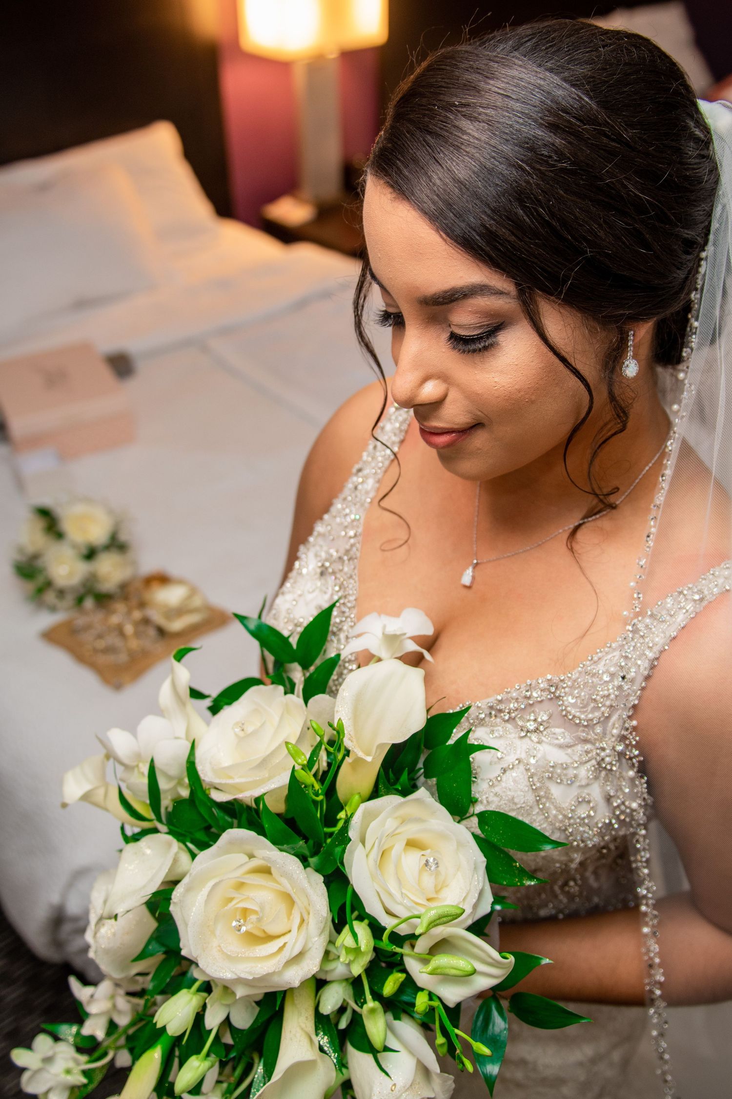 A close-up of a bridal bouquet featuring white roses and elegant jewelry.