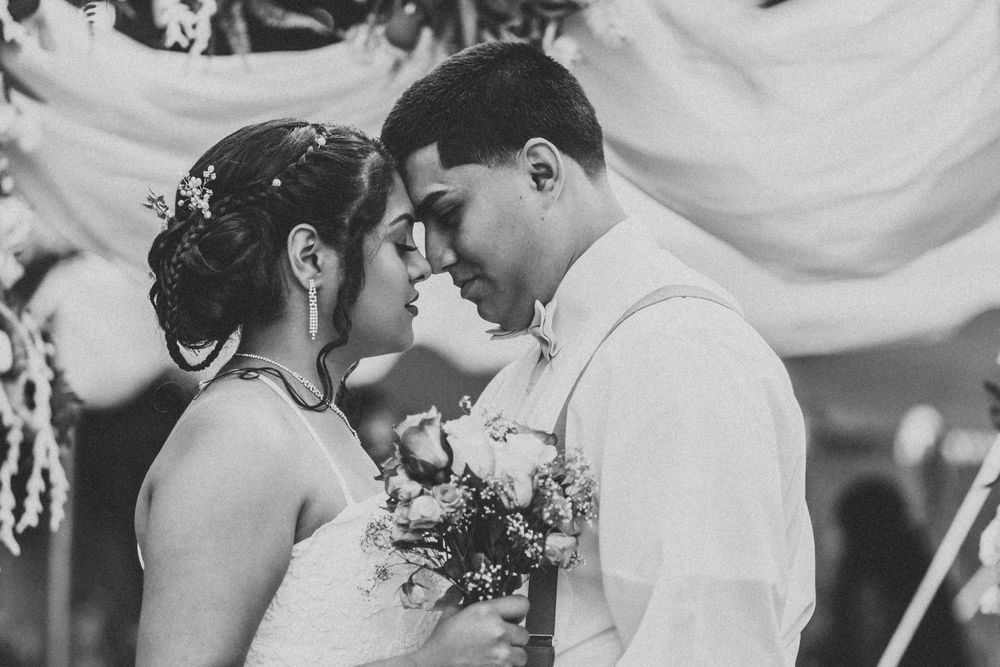 Black and white photo of bride and groom sharing an intimate moment at wedding ceremony.