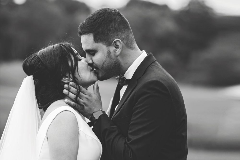 Black and white photo of bride and groom sharing a romantic kiss on their wedding day.
