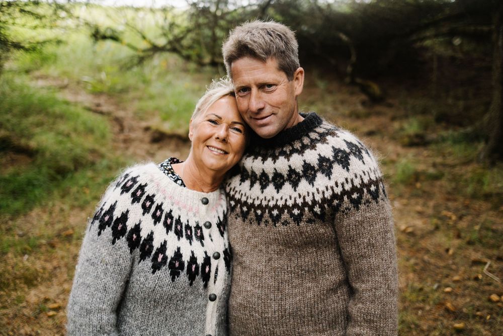 Couple wearing matching Nordic style sweaters outdoors in natural setting.