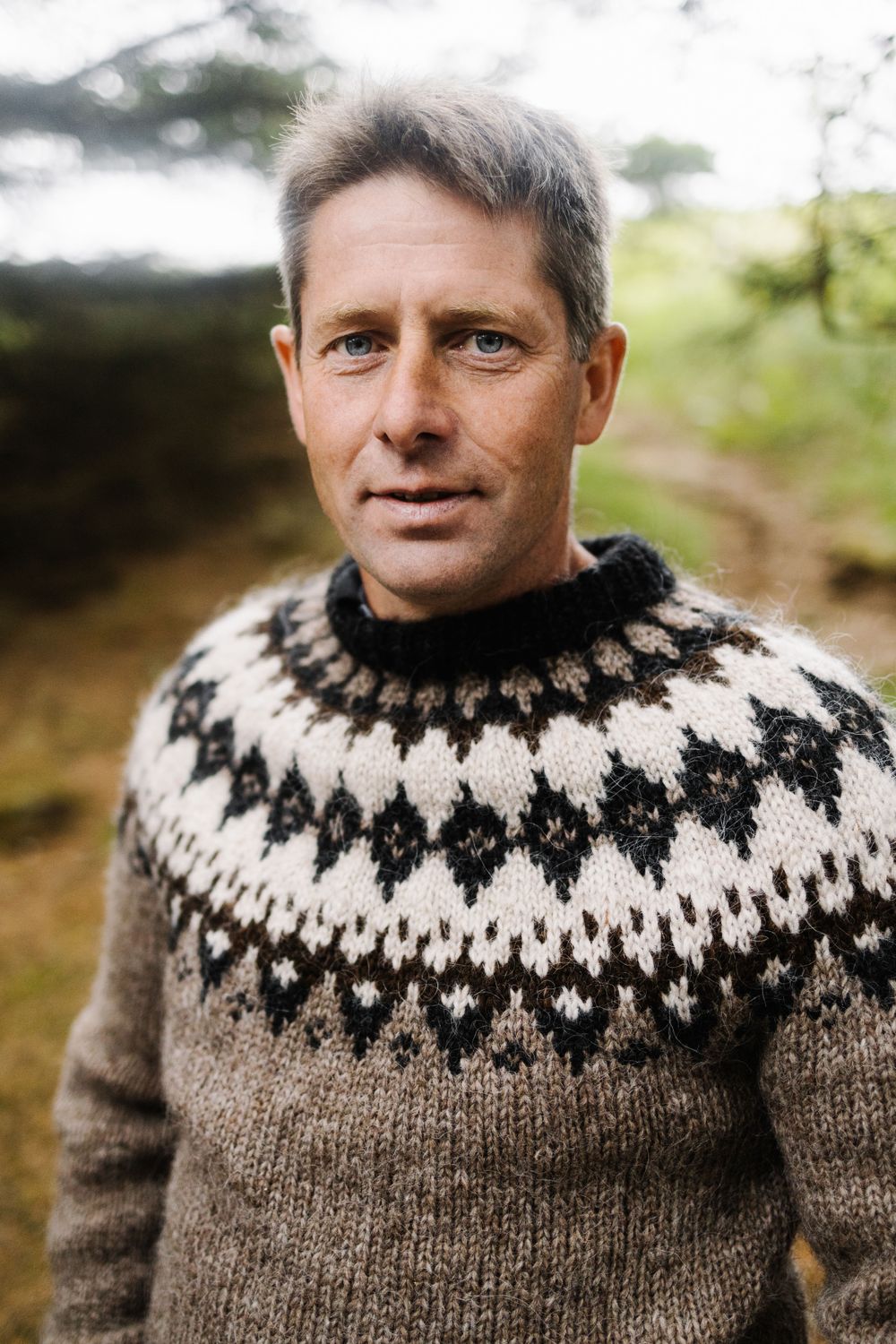 Person wearing traditional Nordic fair isle sweater in brown and white outdoors.