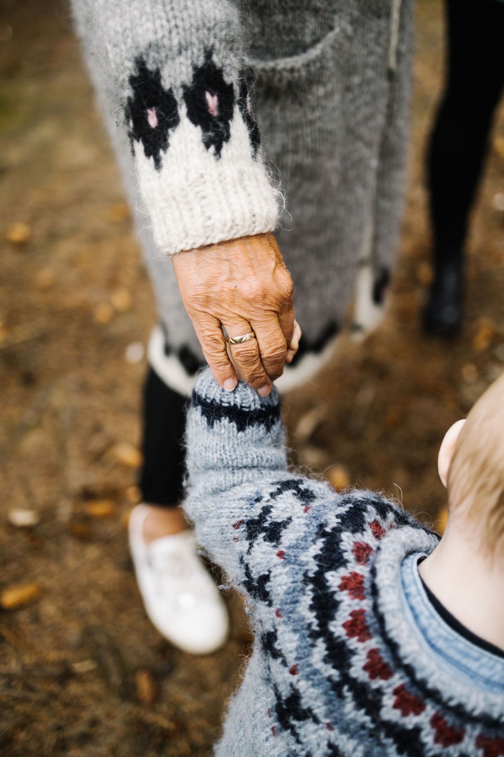 Close-up of hands holding while wearing cozy patterned sweaters in winter.