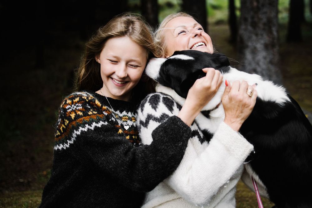 Two people share a genuine moment of laughter while wearing cozy Nordic-pattern sweaters outdoors.