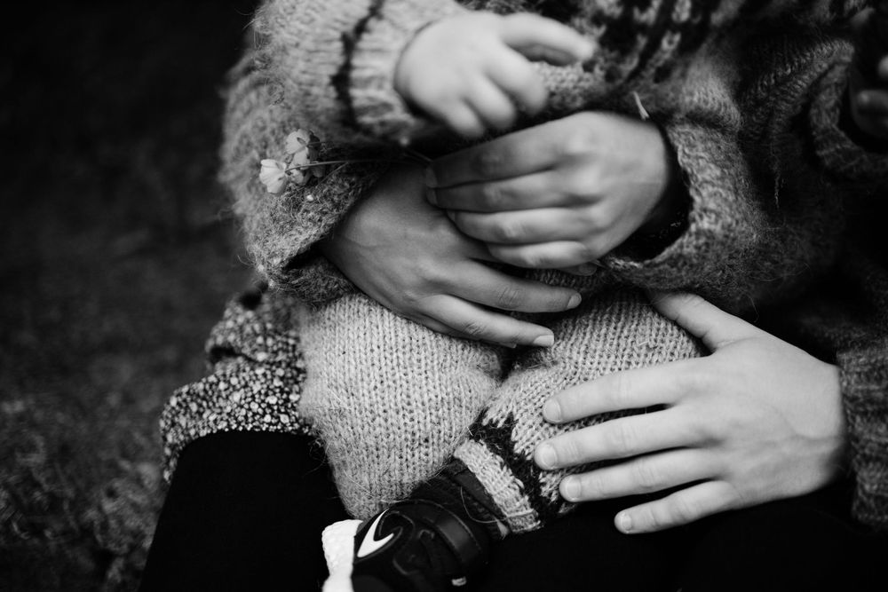 Black and white close-up of hands holding warm knit sweater fabric.