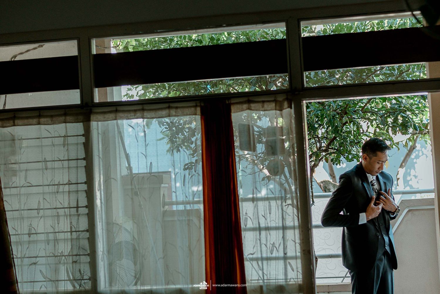 Silhouette by window in formal attire preparing for special occasion.