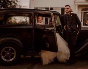 Vintage cars parked outside wedding venue create classic romantic atmosphere.