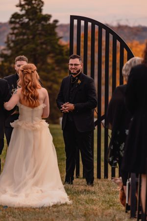 A romantic first look moment between newlyweds at sunset with a decorative gate in the background.