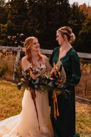 Two people in wedding attire and emerald green share a joyful moment outdoors.