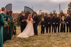 Wedding ceremony guests lined up outdoors wearing emerald green attire.