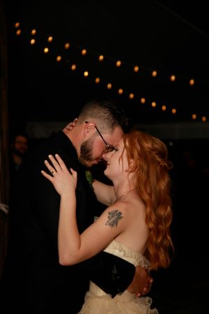 Romantic dance under string lights at an evening wedding reception.