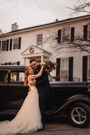 Wedding portraits featuring a classic black vintage car against white colonial architecture.