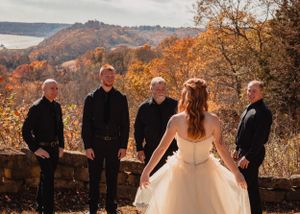 Wedding party poses against autumn mountain landscape in warm evening light.
