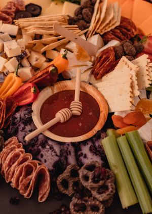 Charcuterie board with meats, cheeses, celery sticks and dipping sauces arranged beautifully.