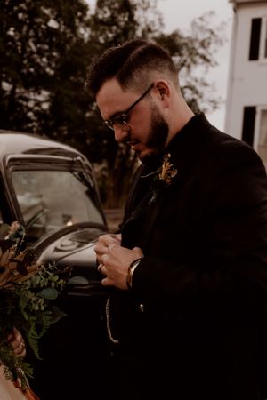 Groomsmen checking their watches before the wedding ceremony near vintage cars.