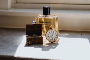 Luxury accessories including a Burberry watch and jewelry displayed on a white surface in natural light.