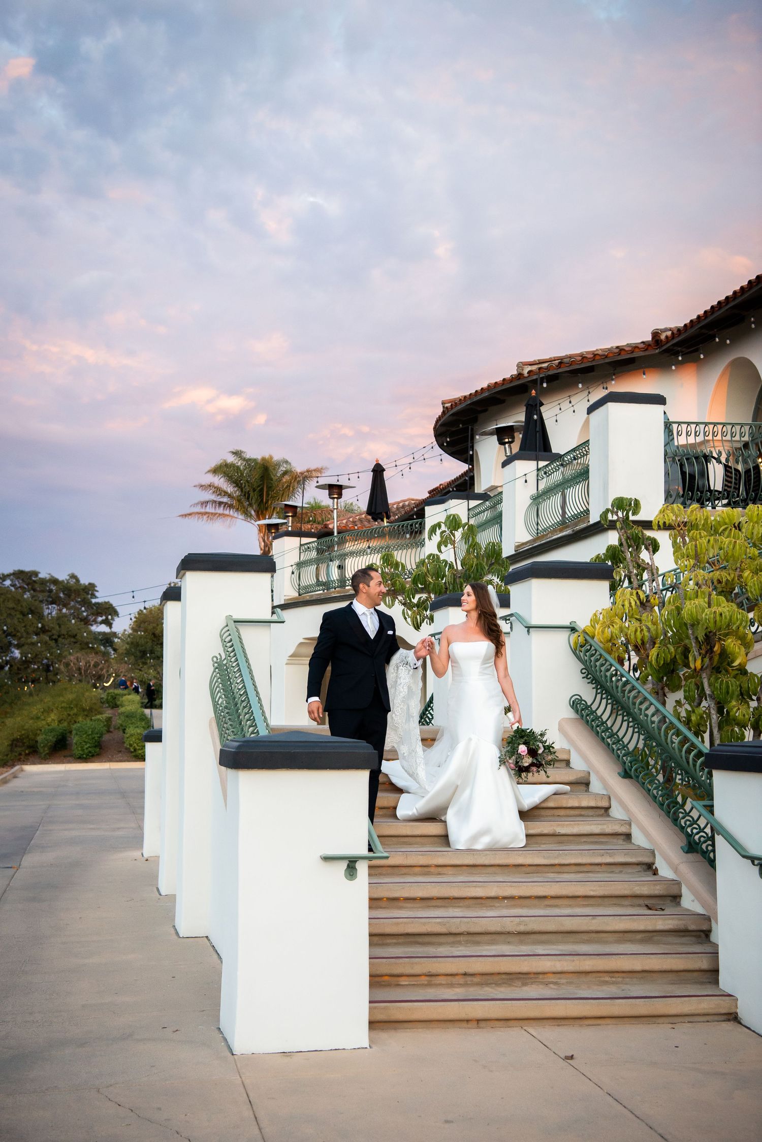 A Spanish-style estate with white stucco walls and ornate railings at sunset.