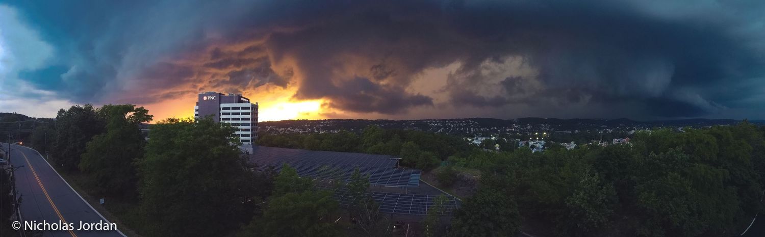 Dramatic sunset sky with dark storm clouds over a rural landscape.