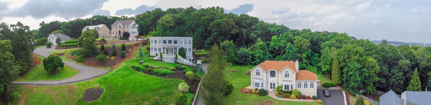 Wide aerial panorama of luxury homes and green landscapes along waterfront property.
