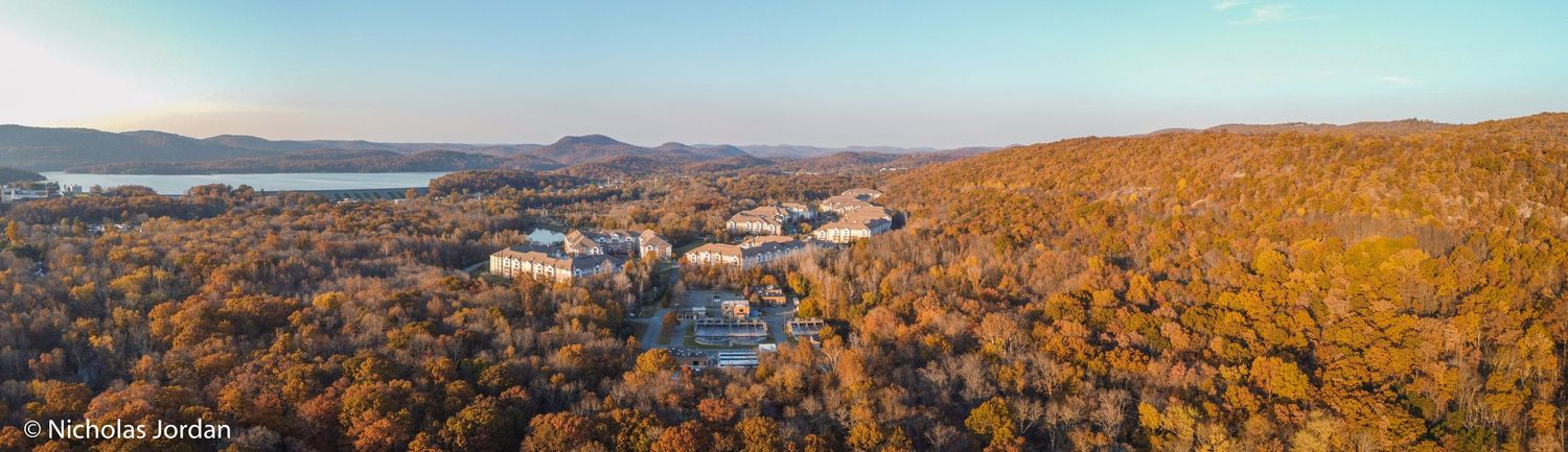 Scenic autumn landscape showing colorful fall foliage and residential areas from above.