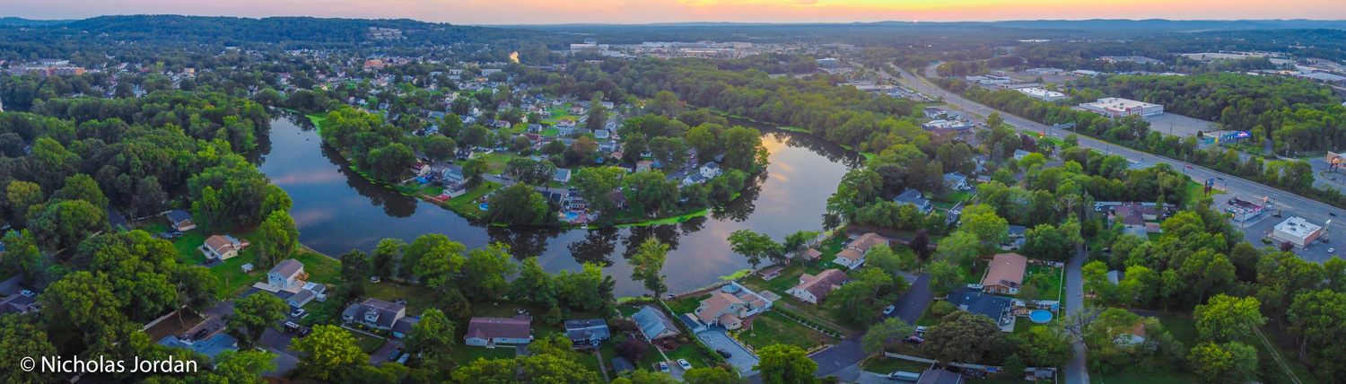 Aerial panorama of waterfront community with mountains in background during sunset.
