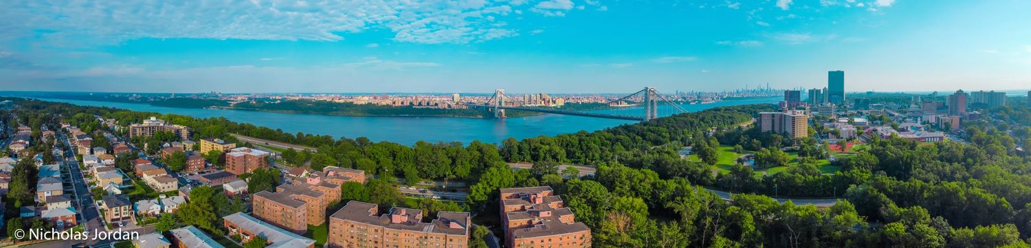 Panoramic aerial view of coastal homes and waterways under bright blue skies.