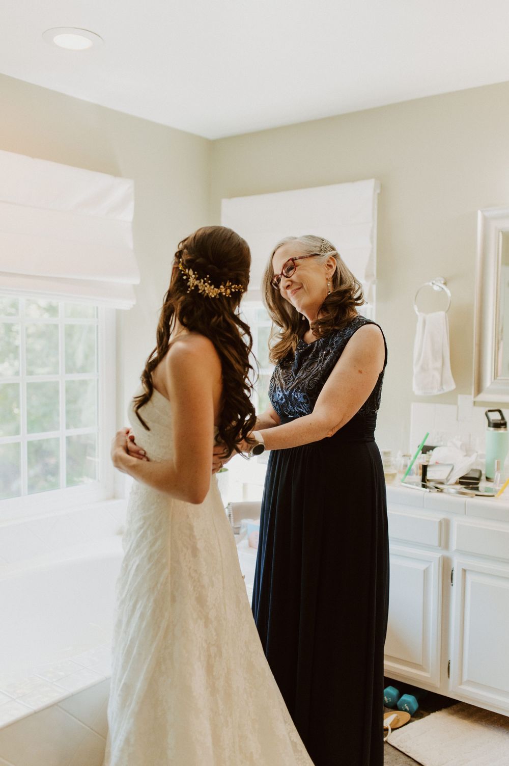 Wedding dress fitting scene with final adjustments being made in bright room.