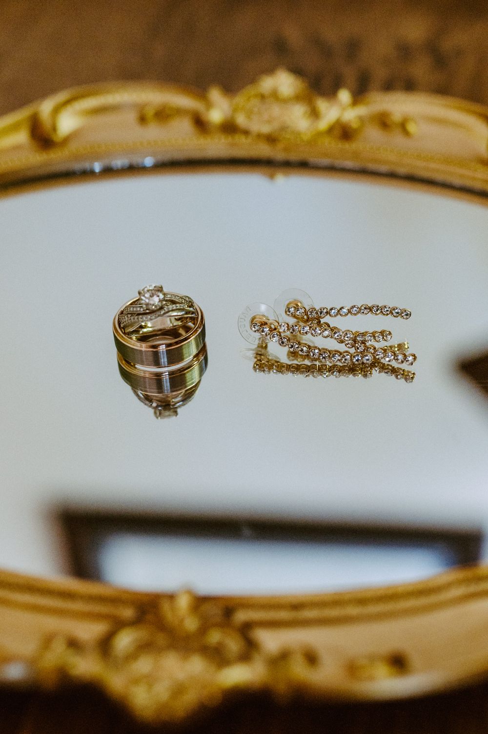 Wedding rings and jewelry displayed on ornate white and gold surface.