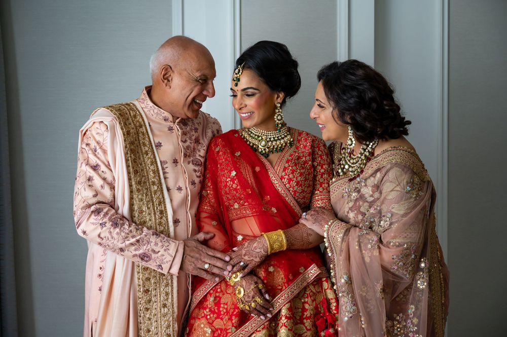 Bride with her mum and dad at Fairmont Windsor by Foto Collective, bride in red and gold lehenga sharing a tender family moment.