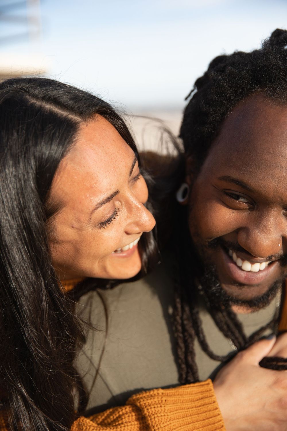 Two people sharing a close, intimate moment together while smiling and laughing in warm lighting.