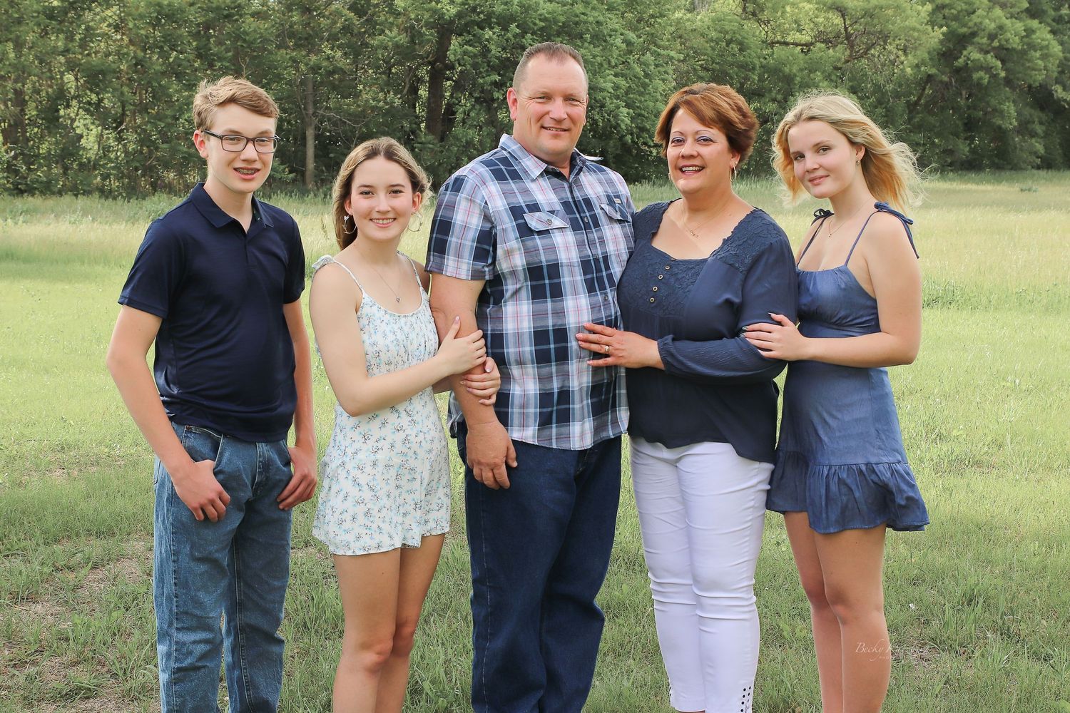 becky katzberg photography family summer photo in a grassy field with tall trees in the background