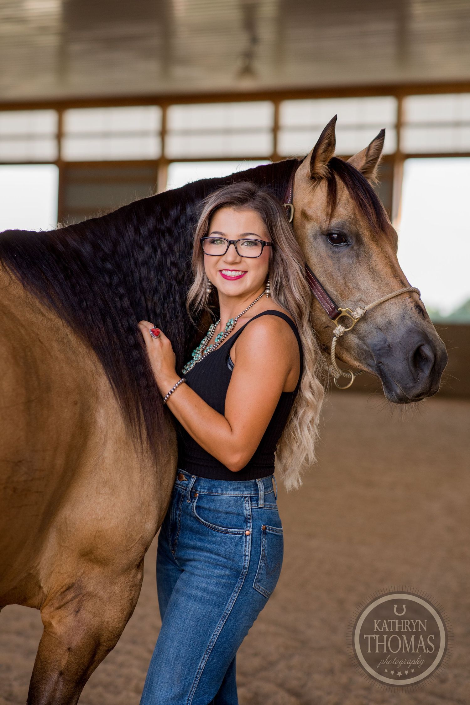 A majestic brown horse poses with its handler in an indoor riding arena.