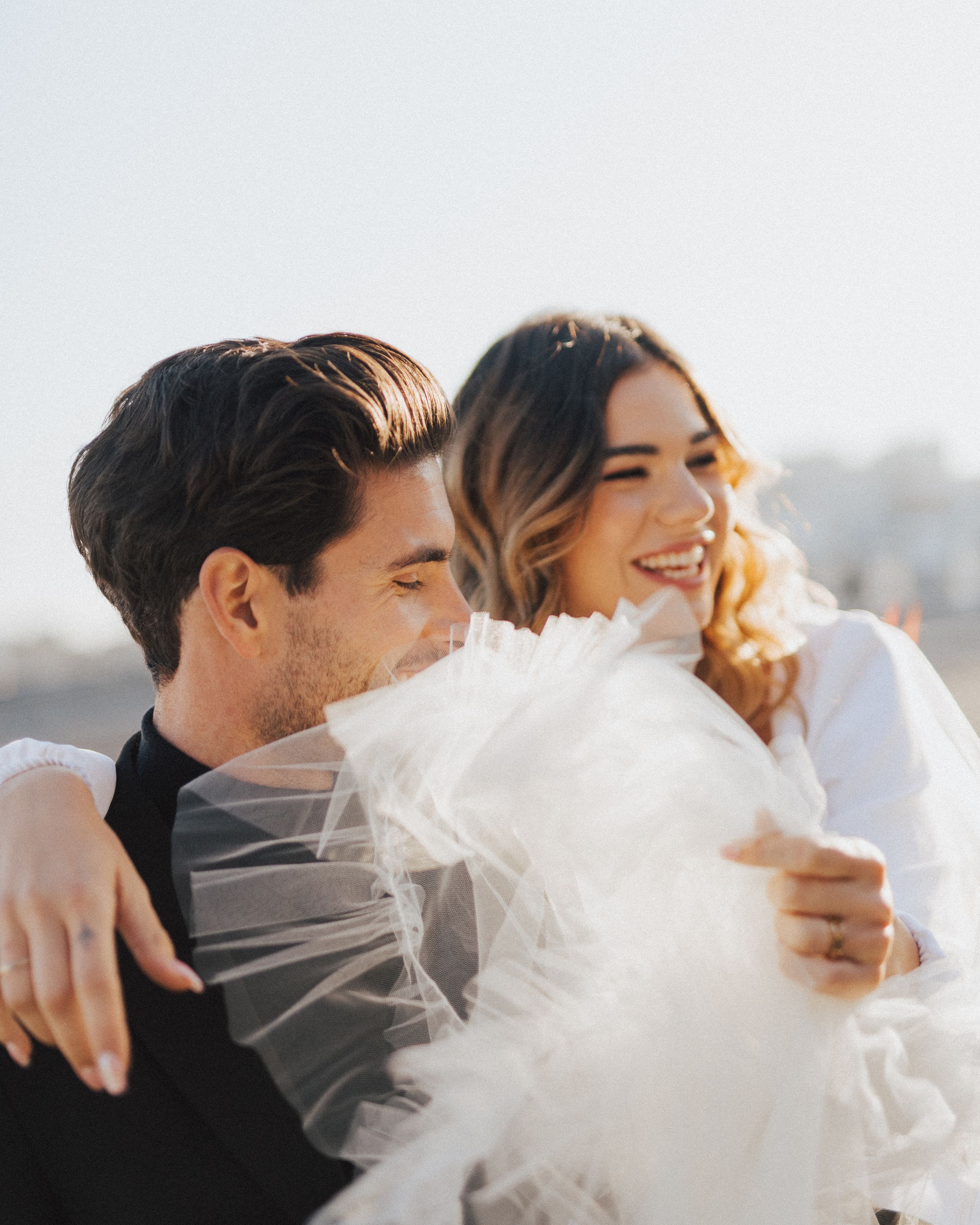 Intimate wedding couple portraits with flowing veil in golden sunlight.