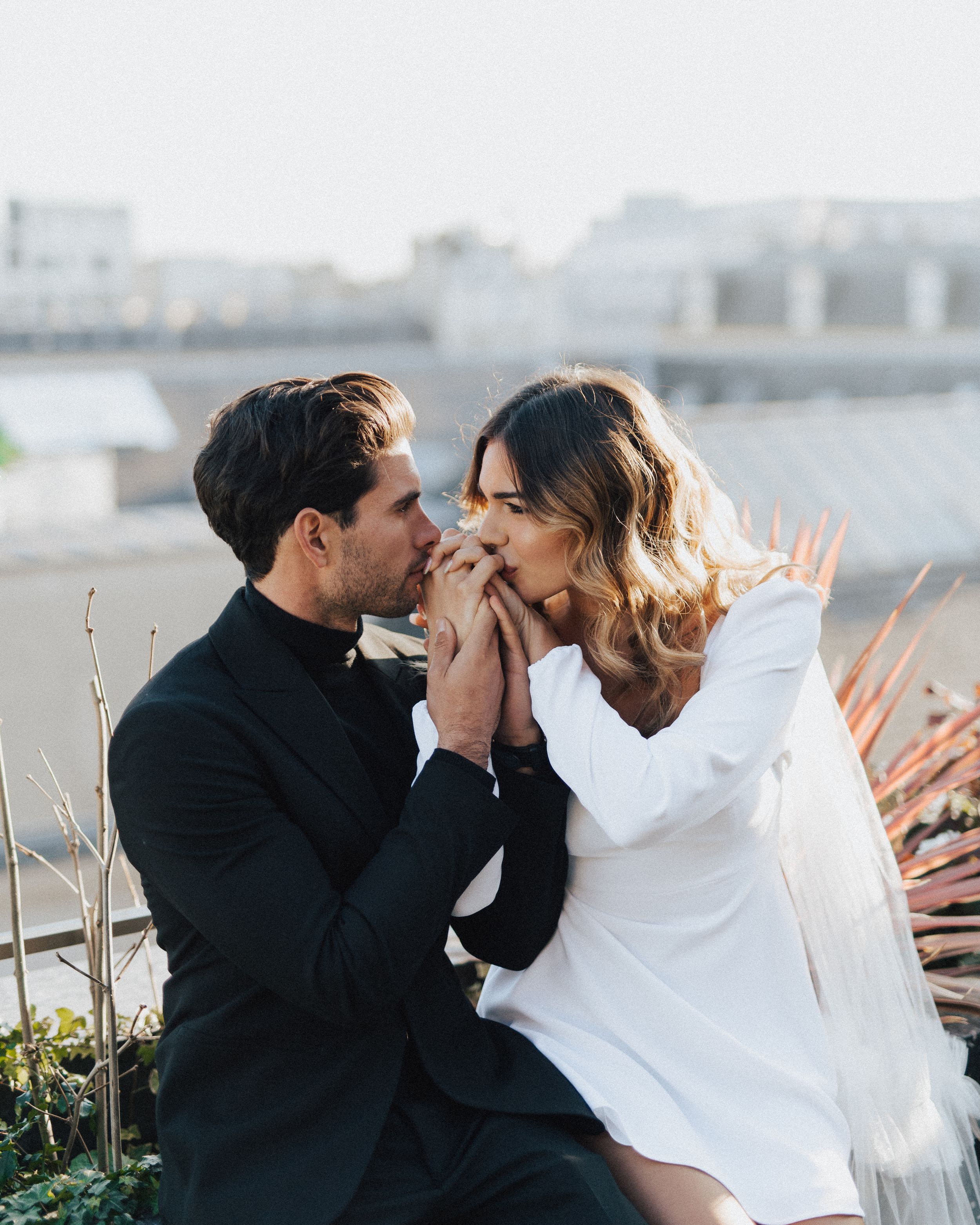 Romantic rooftop photoshoot with couple in white and black outfits.